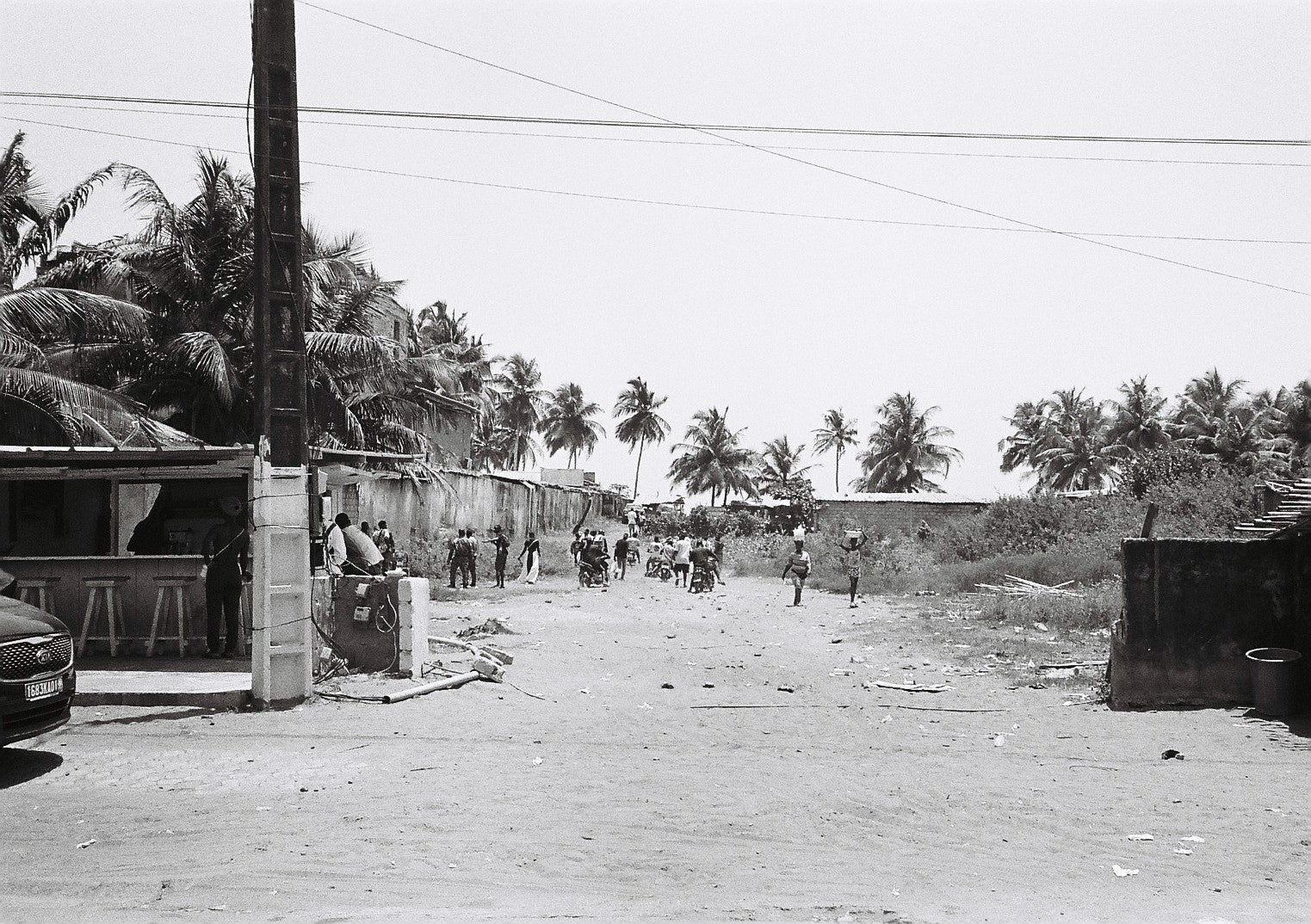 Black and white street scene with people, buildings, and palm trees.