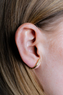 Maison Nwar curved stud earring worn on ear, close-up profile view
