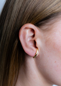 Model wearing Maison Nwar curved gold vermeil stud earring, close-up ear shot