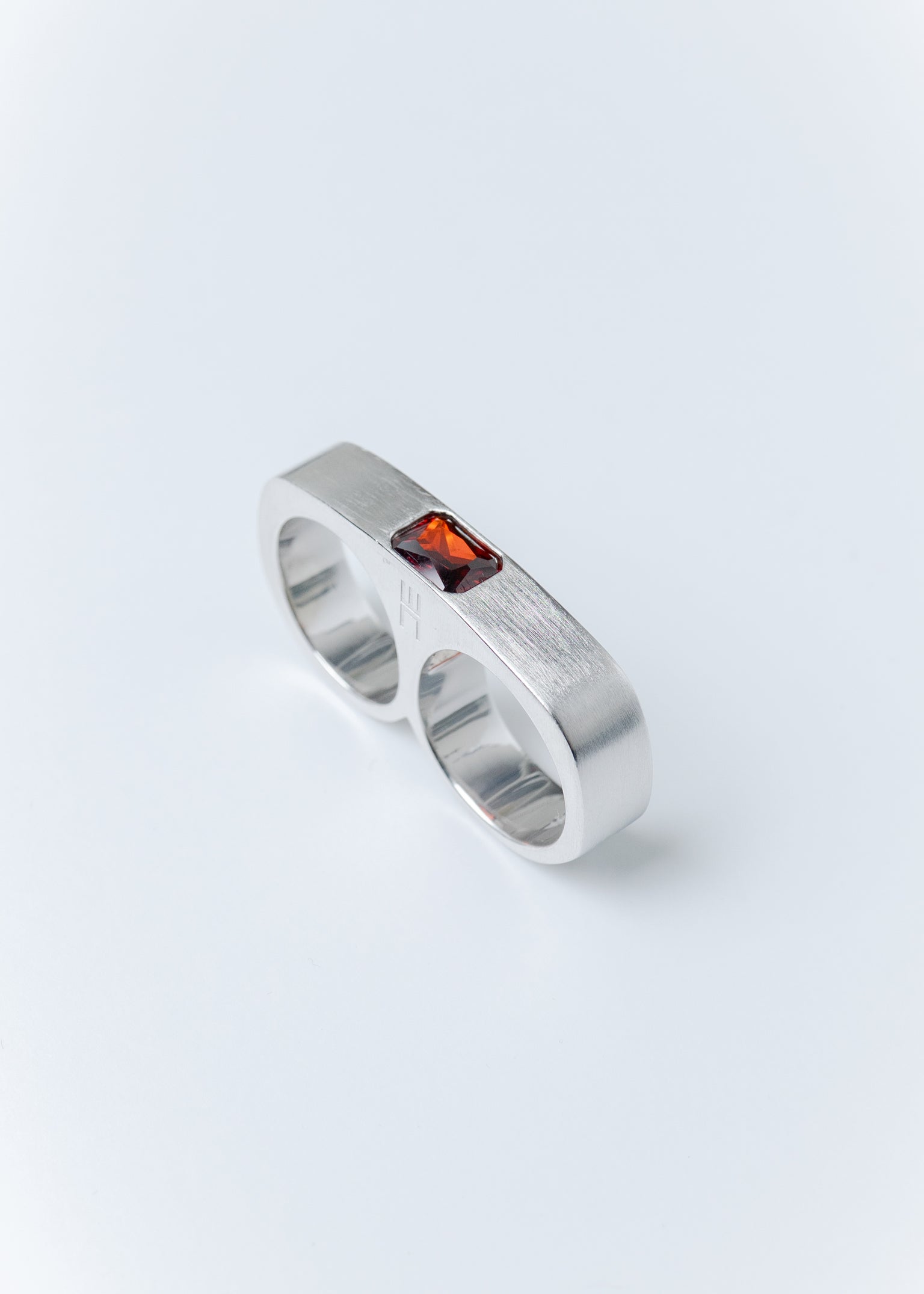 Maison Nwar sterling silver ring with red gemstone detail on light gray background