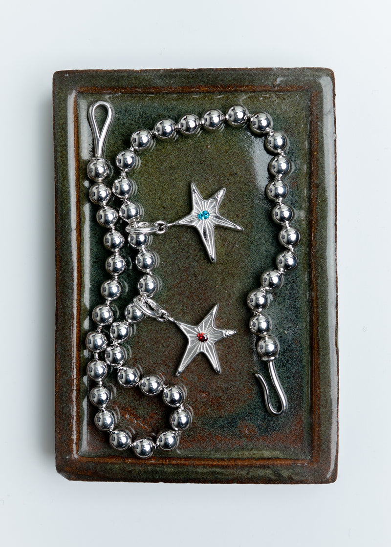 Maison Nwar star pendant displayed in branded packaging, top view