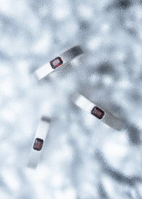 Three silver rings with red stones arranged on a textured icy surface