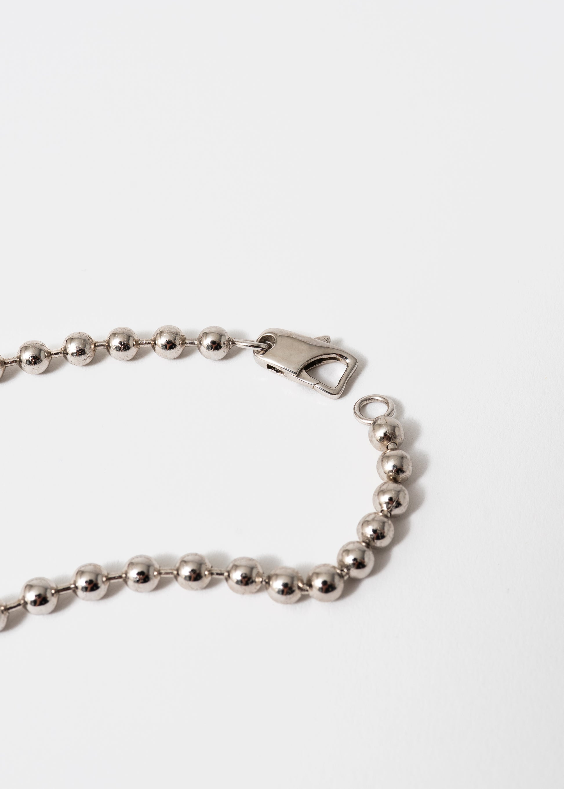 Maison Nwar signature necklace worn on chest — sterling silver and gold tones with deep red stone