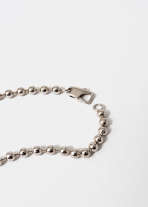 Maison Nwar signature necklace worn on chest — sterling silver and gold tones with deep red stone