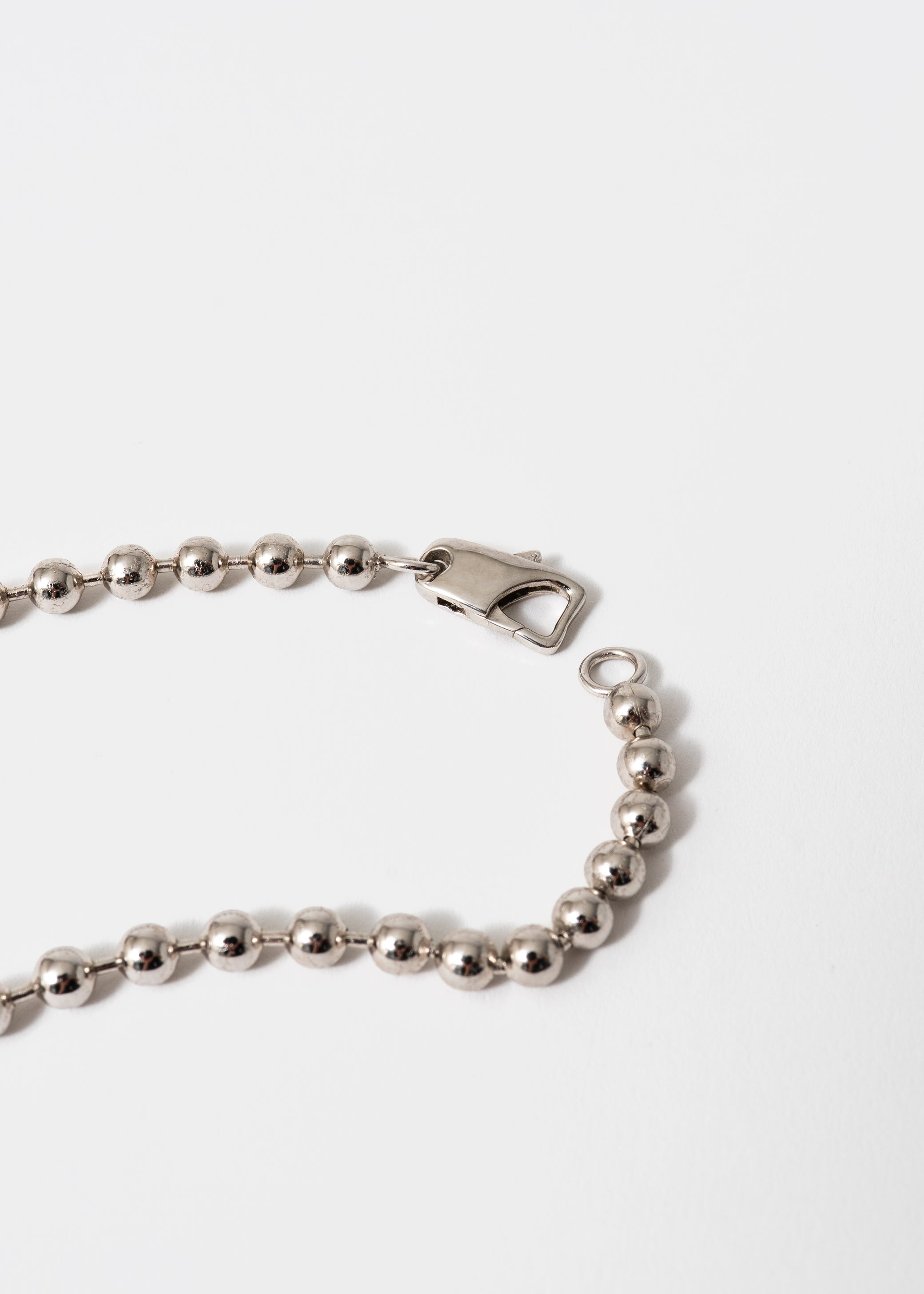 Maison Nwar signature necklace worn on chest — sterling silver and gold tones with deep red stone
