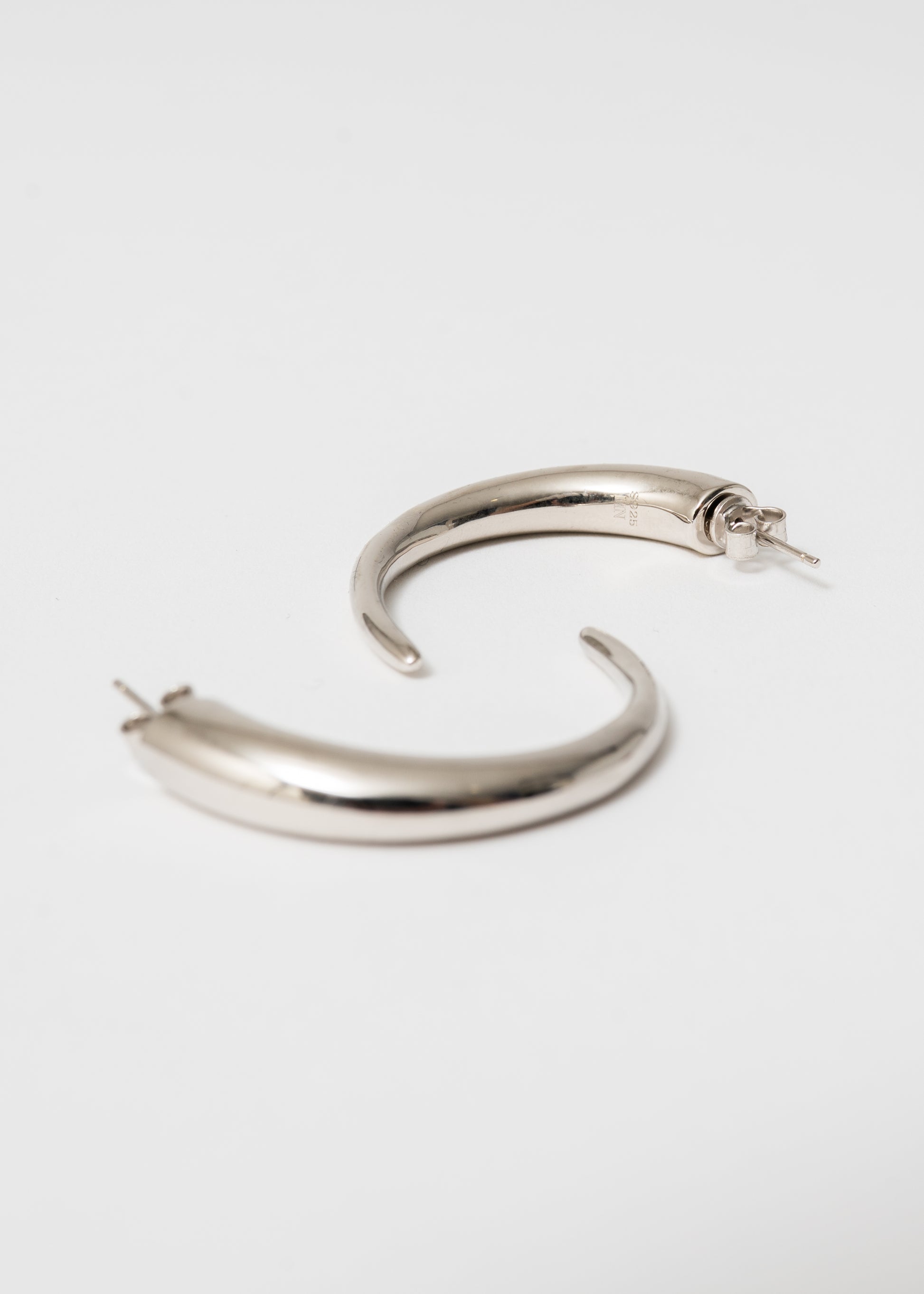 Close-up of Maison Nwar sterling silver hoop — high-polish finish and sculptural shape