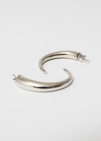 Close-up of Maison Nwar sterling silver hoop — high-polish finish and sculptural shape