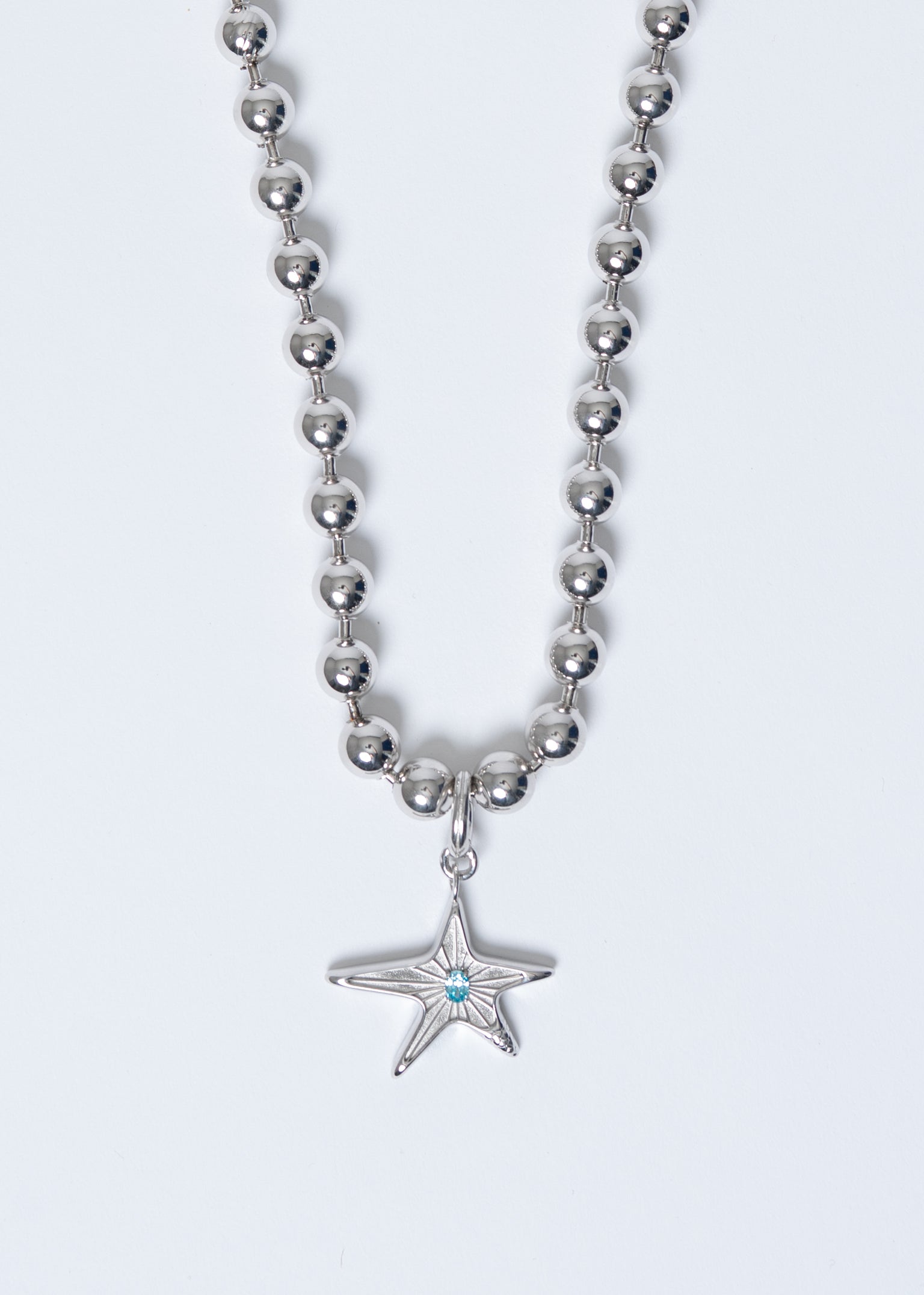 Maison Nwar star pendant necklace in sterling silver with blue stone detail, studio shot