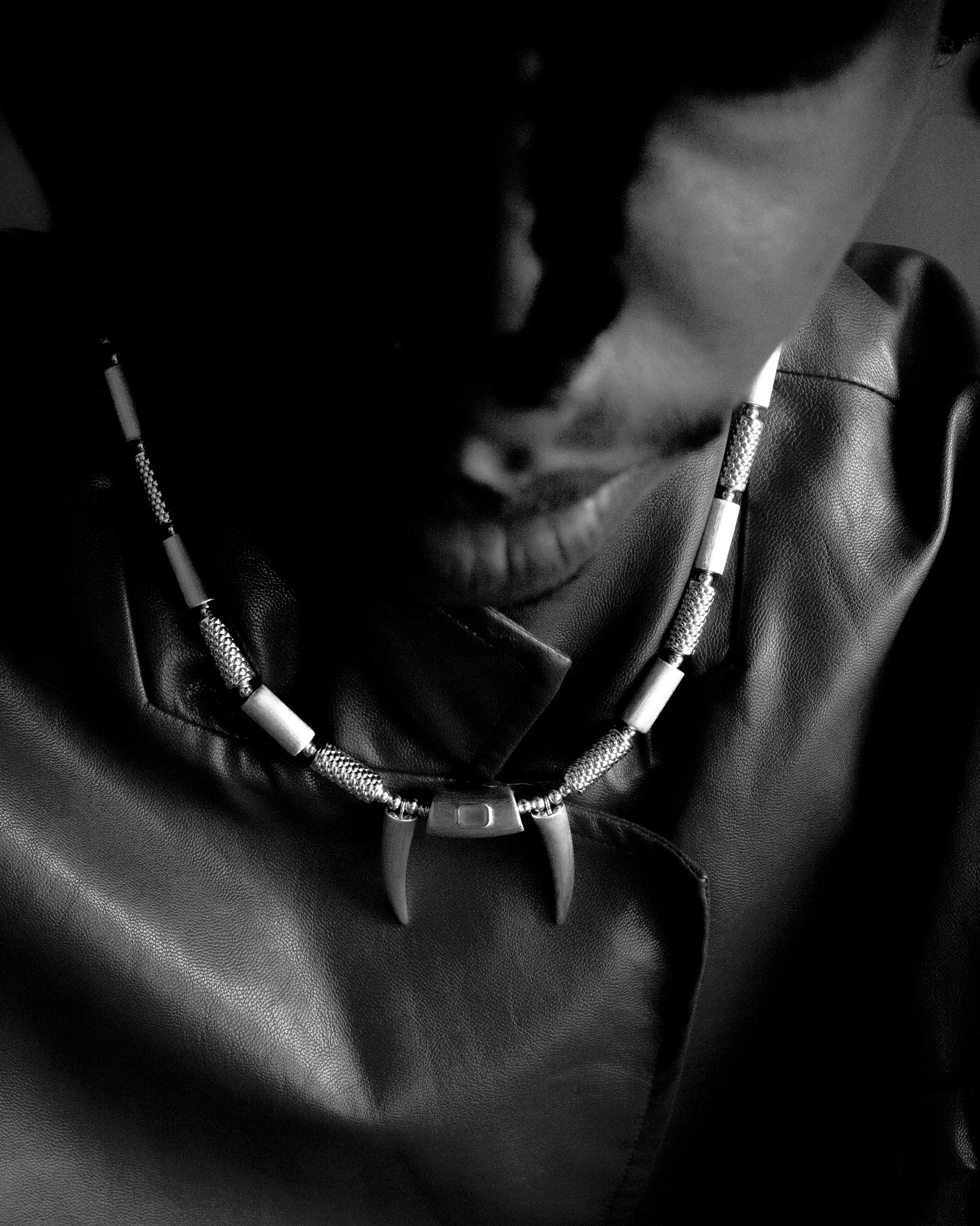 Person in a red outfit wearing a necklace with pendants against a red background.