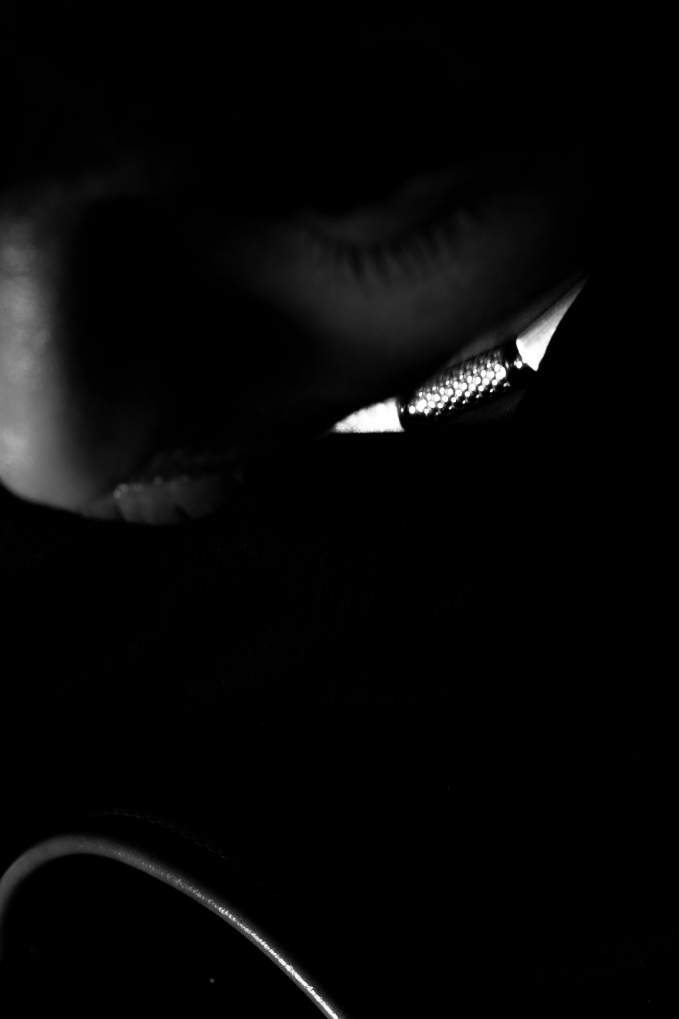 Close-up of a partially lit face with a metallic detail in shadow.