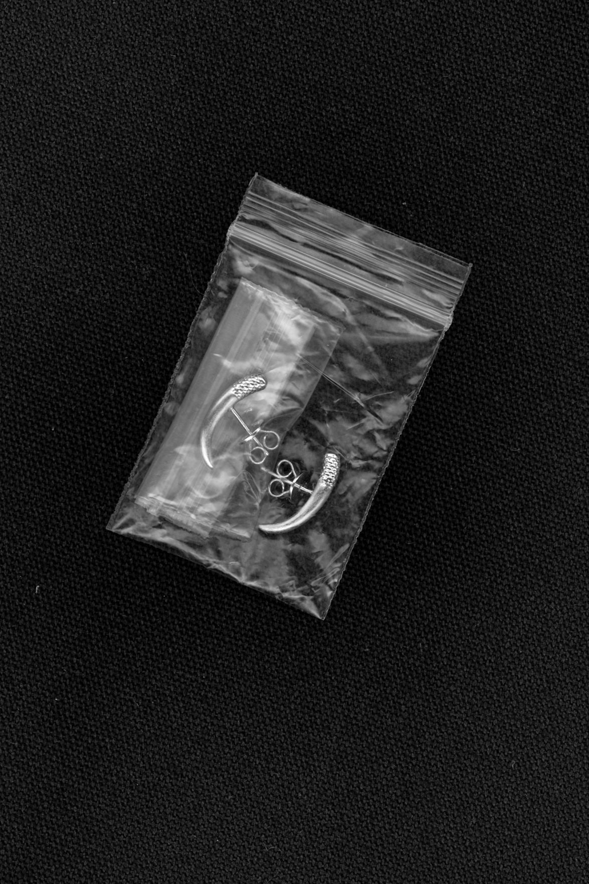 Hands holding a circular metal object with a silver ring at the center on a dark background.