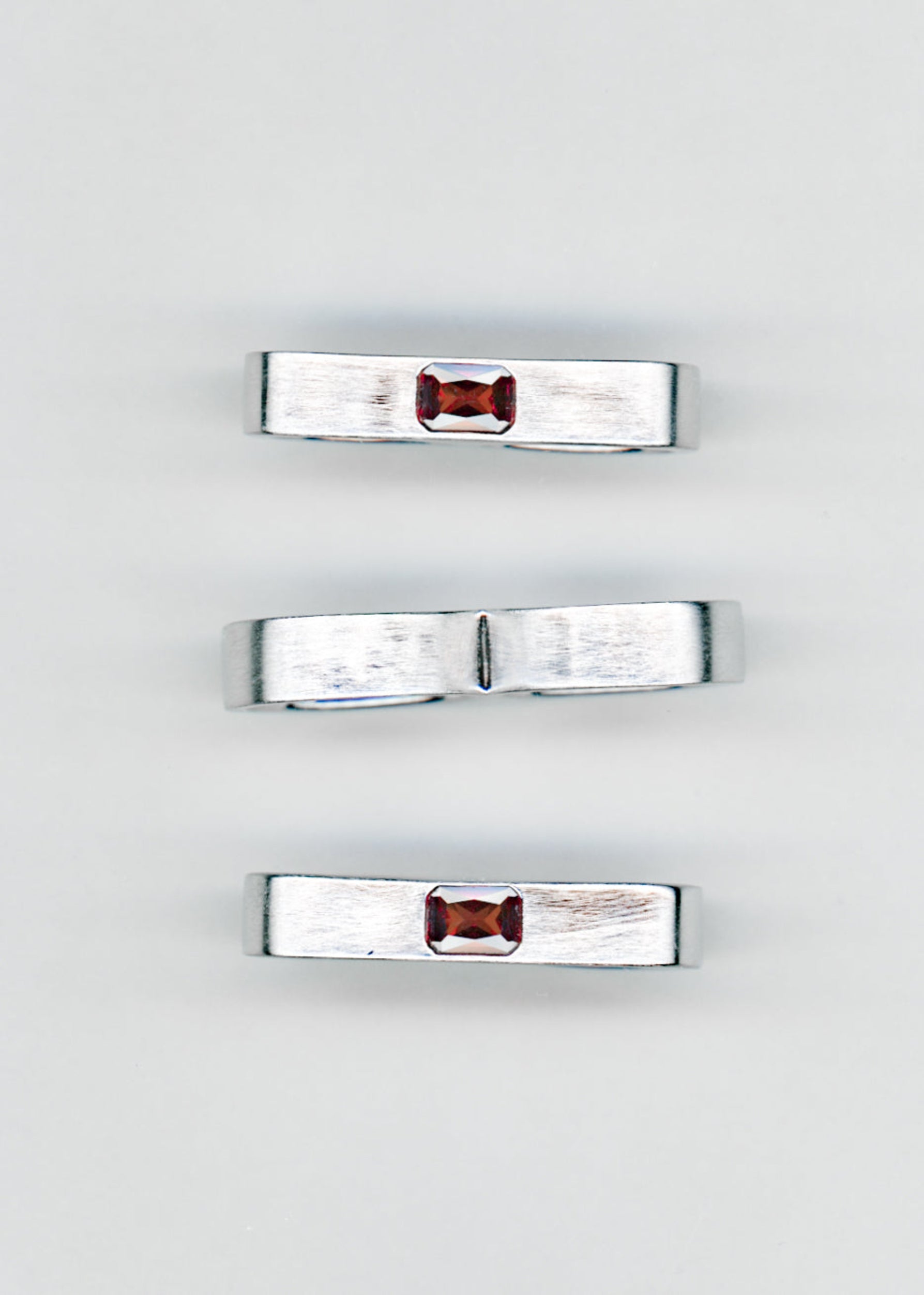 Maison Nwar ring collection flat lay, multiple silver bands with red gemstones