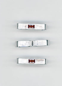 Maison Nwar ring collection flat lay, multiple silver bands with red gemstones