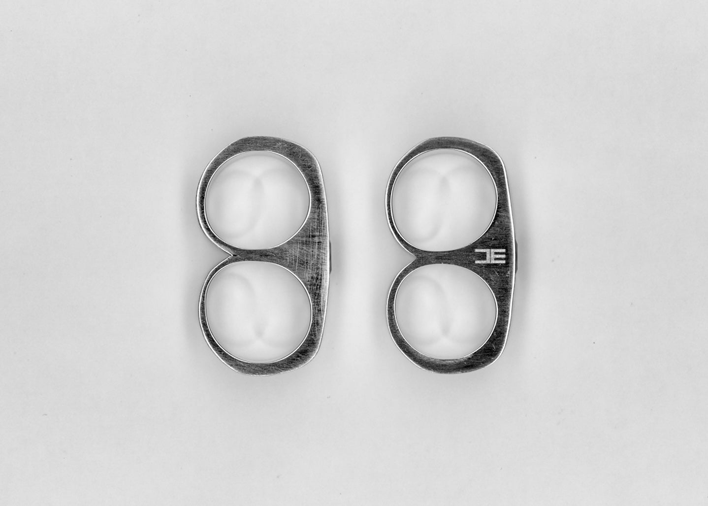 Two metal pieces with circular cutouts on a light background.