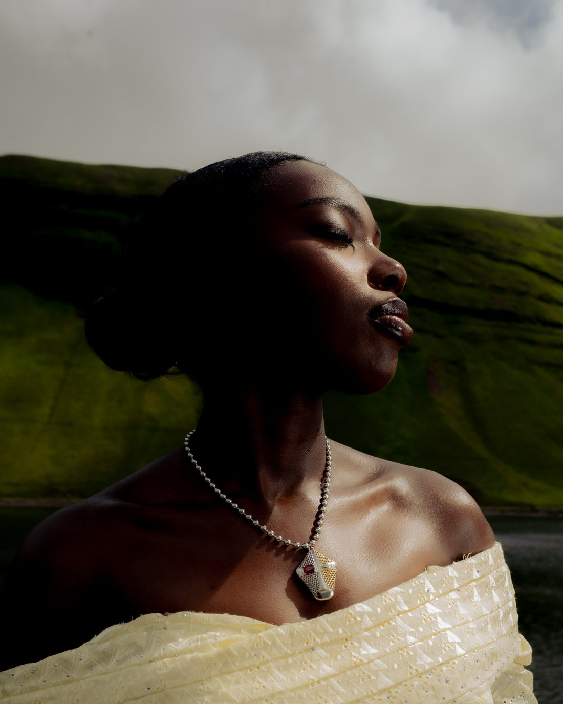 Senegalese woman wearing Maison Nwar jewelry in traditional clothing, photographed in the hills of Wales.